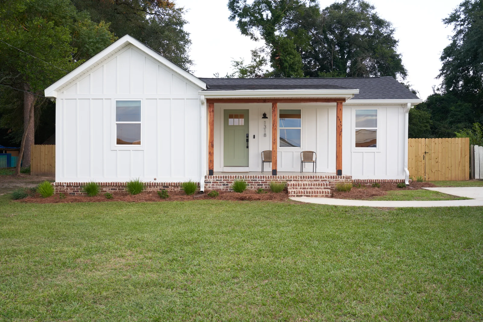 Full daylight view of Historic Perry Cottage, its front porch, and lawn