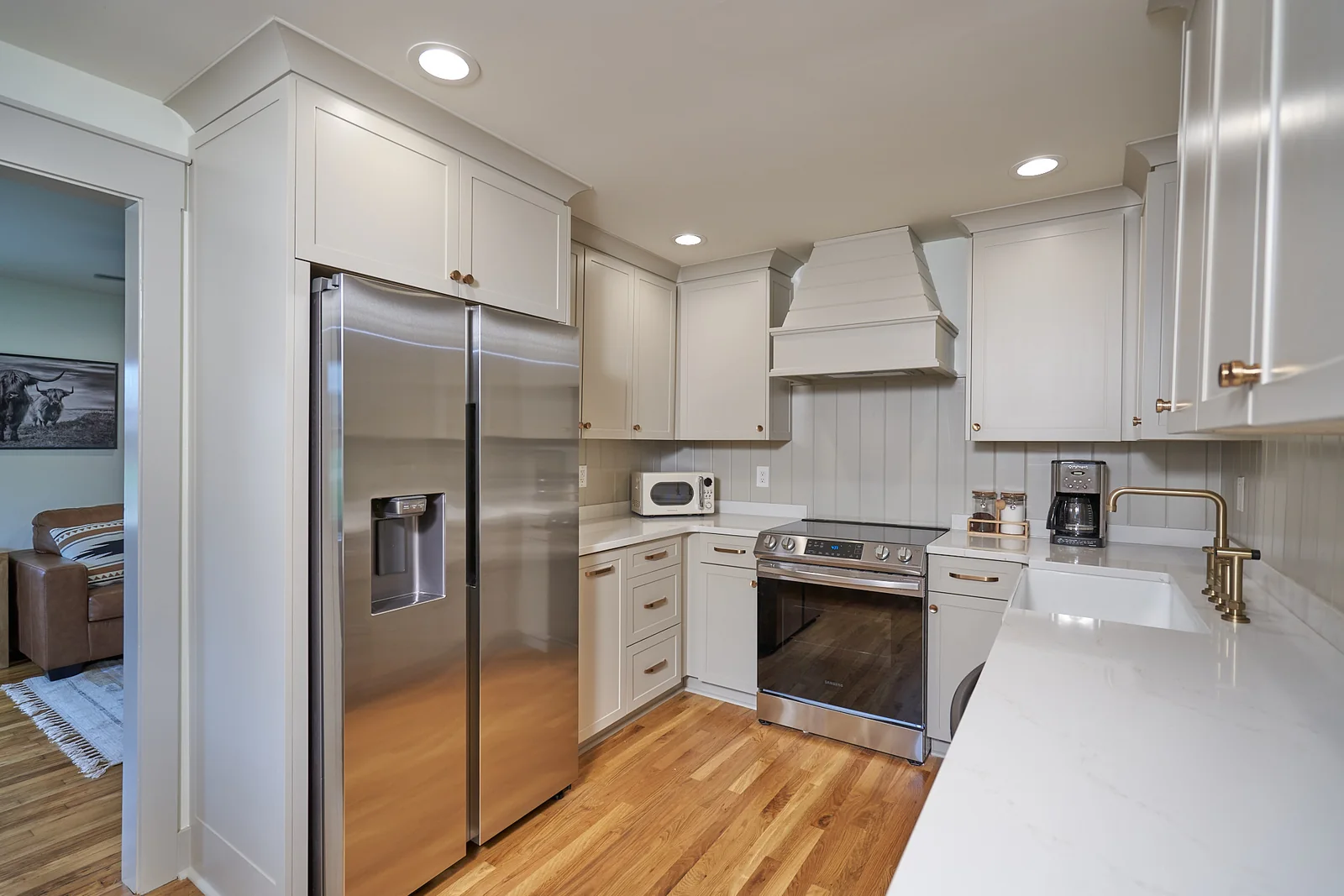 Cottage kitchen with white cabinets, stainless steel appliances, and wood floors